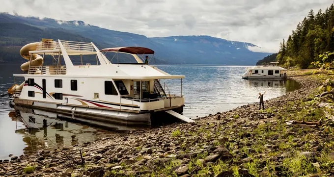 A family enjoying a houseboat vacation while parked on the shoreline of Shuswap Lake; Shuswap Lake, British Columbia, Canada