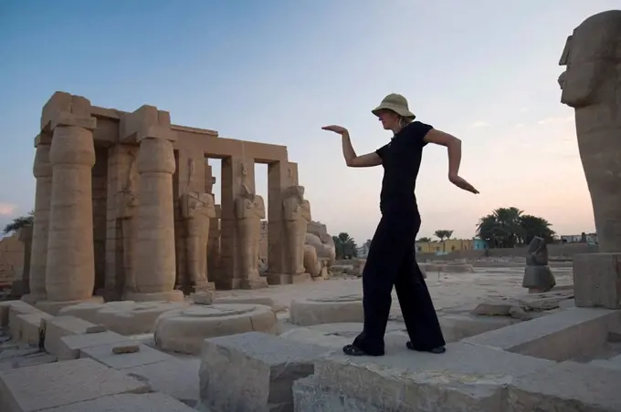 Woman tourist walks like an Egyptian at the Ramesseum, Luxor, Nile Valley, Egypt