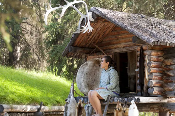 Alaskan Native Indian Guide Sitting In A Cache Speaking About Furs At An Athabascan Village On The Riverboat Discovery Tour, Fairbanks, Interior Alaska, Summer