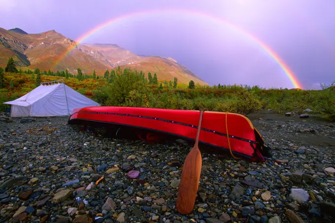 Canoe And Tent At A Campsite With A Rainbow And The Mackenzie Mountains In The Background In Autumn, Snake River, Whitehorse, Yukon