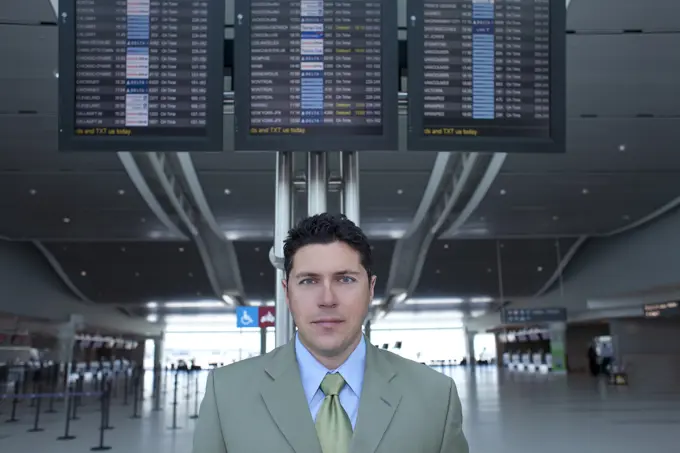 Businessman At Airport In Front Of Flight Information Monitors, Toronto, Ontario, Canada