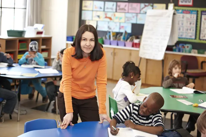 Teacher Helping Young Grade 3 Boy At His Desk In Classroom; Toronto Ontario Canada