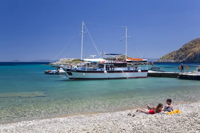 Sunbathers enjoying Sesklia Beach on Symi Island in Greece; Symi, Dodecanese, Greece