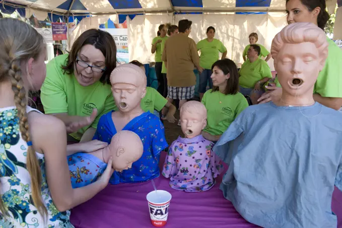 Woman teaches how to perform the Heimlich maeuver at a booth; Saint Paul, Minnesota, United States of America