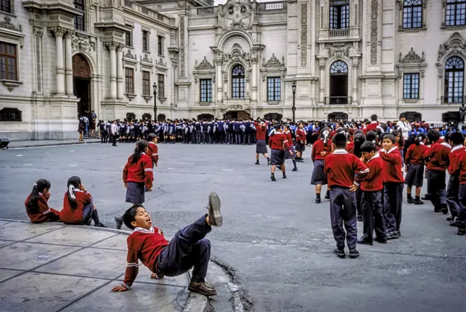 School children dressed in red uniforms play at the Plaza de Armas in Lima, Peru