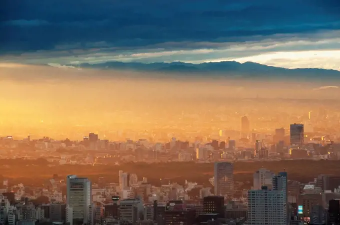 Japan, Sunlight At Sunrise Over Cityscape With Mountains In Background; Tokyo