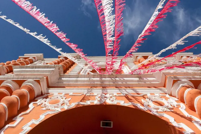 White and red streamers blowing in the wind strung above a building´s doorway, guatemala city guatemala