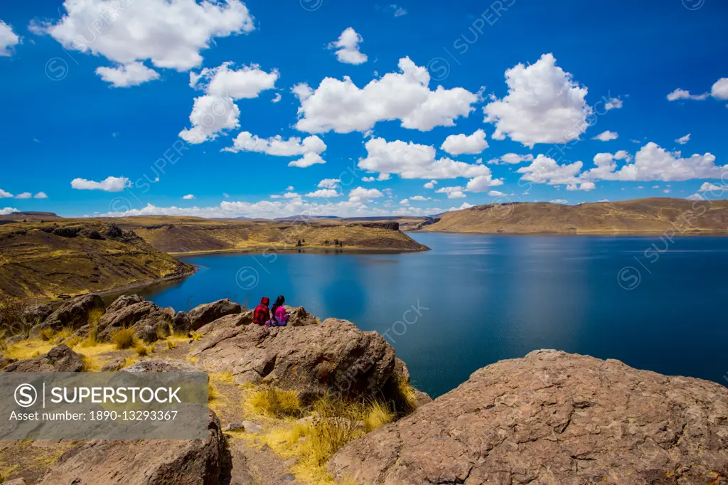 Two people sitting on the edge of Lake Titicaca, Peru, South America