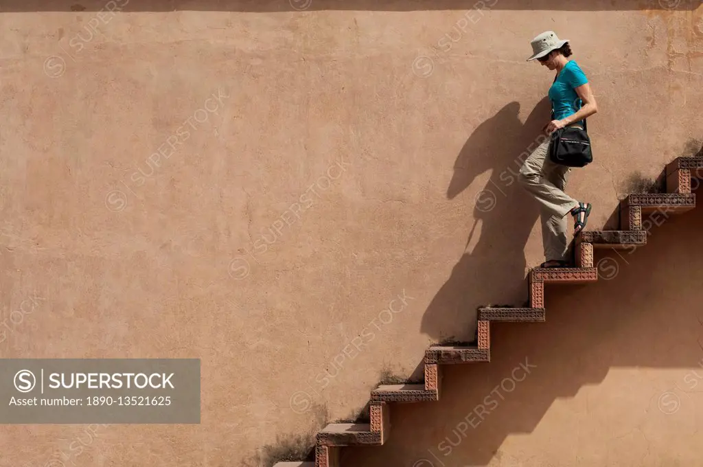 A tourist climbs downs some exposed steps within the Fatehpur Sikri temple complex, Uttar Pradesh, India, Asia