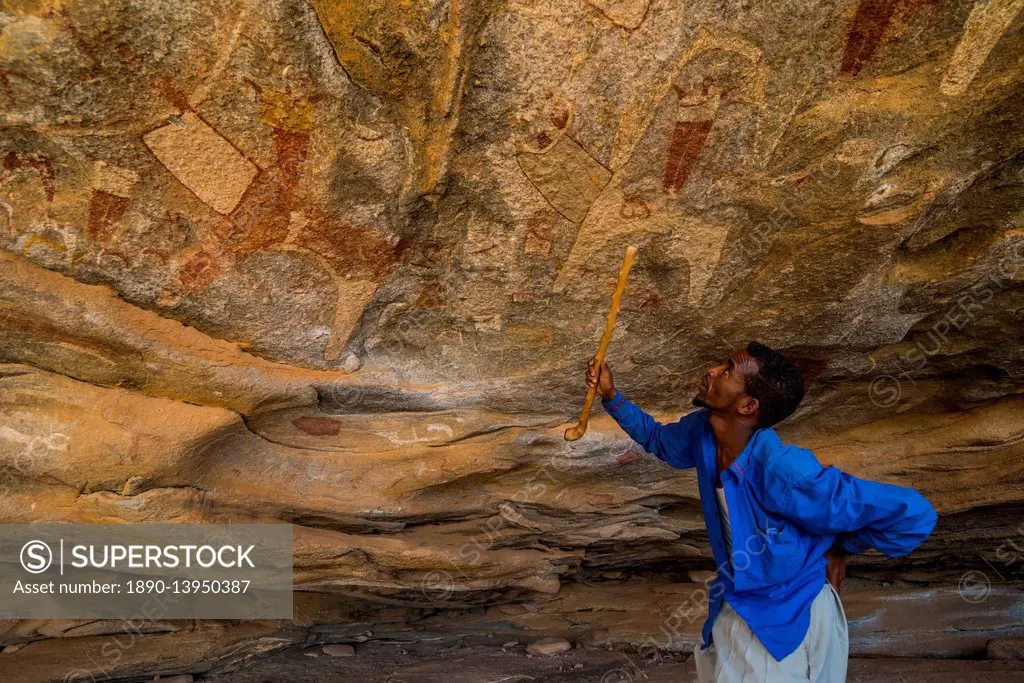 Guide pointing at cave paintings in Lass Geel caves, Somaliland, Somalia, Africa