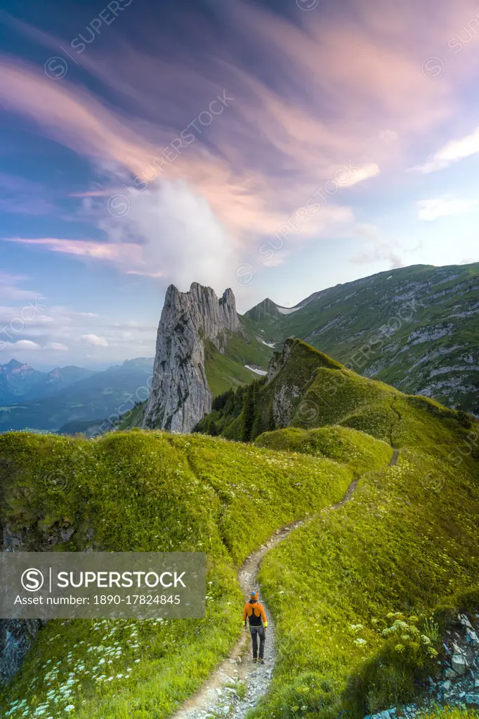 Hiker man walking on footpath towards Saxer Lucke at sunset, Appenzell Canton, Alpstein Range, Switzerland, Europe