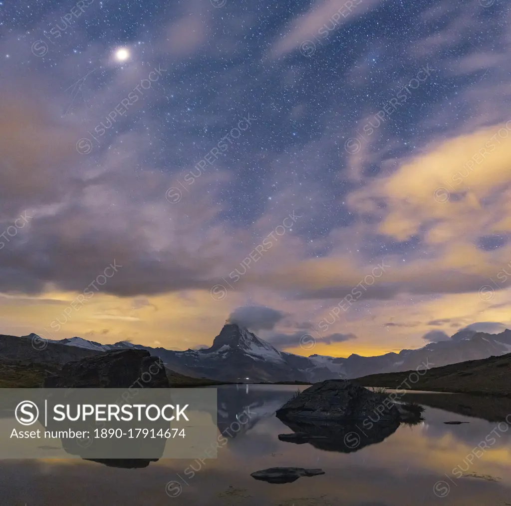 Matterhorn peak lit by moon in the starry night sky viewed from Stellisee, Zermatt, Valais canton, Switzerland, Europe