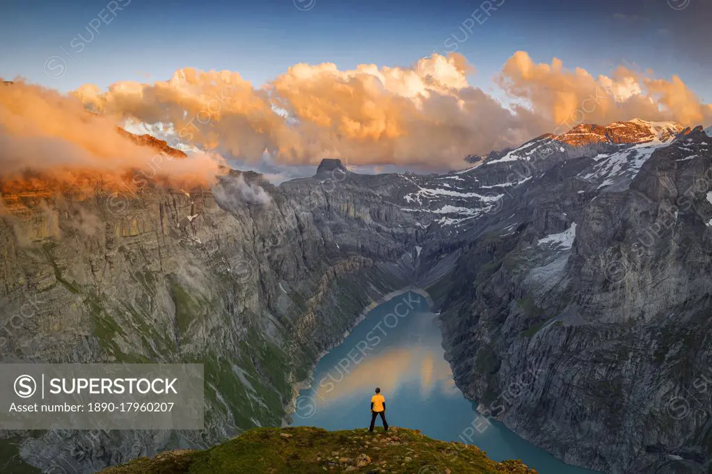 Man standing on rocks looking at clouds at sunset over lake Limmernsee, aerial view, Canton of Glarus, Switzerland, Europe