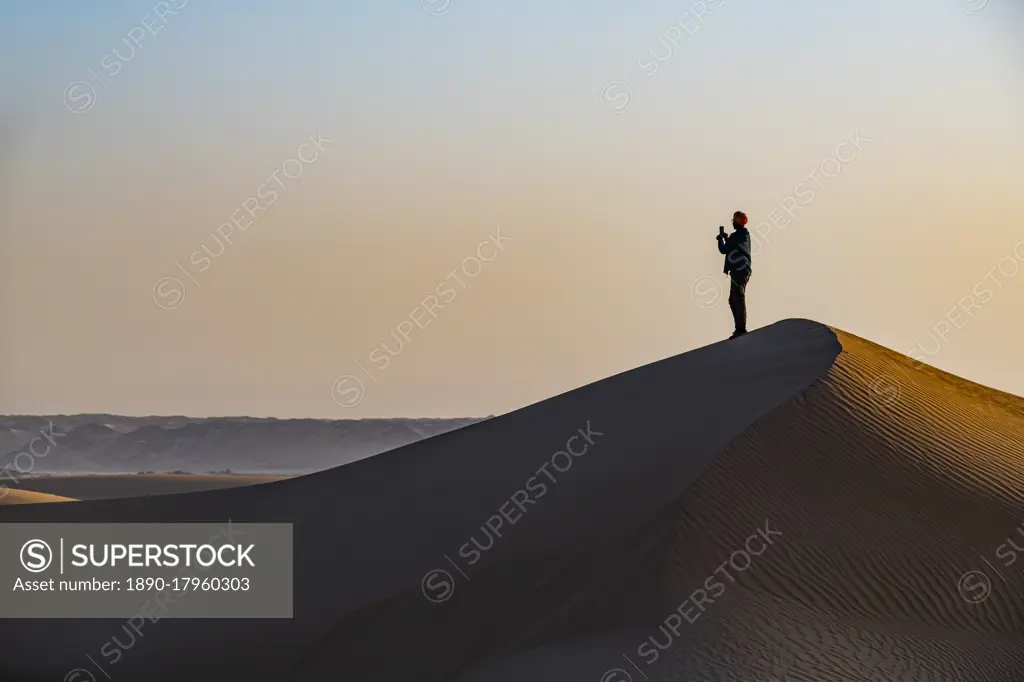 Man hiking through the sand dunes, Dirkou, Djado Plateau, Sahara, Niger, Africa