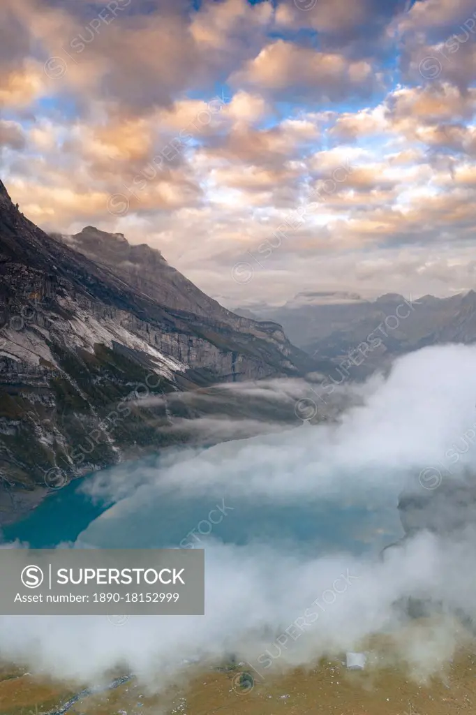 Clouds at sunset over the pristine lake Oeschinensee in the mist, Bernese Oberland, Kandersteg, canton of Bern, Switzerland, Europe