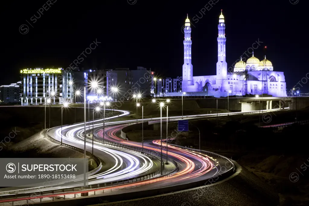 Long exposure cityscape night shot with a blue mosque and a street with car trails, Muscat, Oman, Middle East