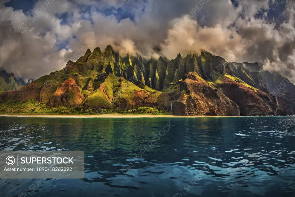 The Cathedral of the NaPali Coastline towers over the calm summer waters at sunset, Hawaii, United States of America, Pacific
