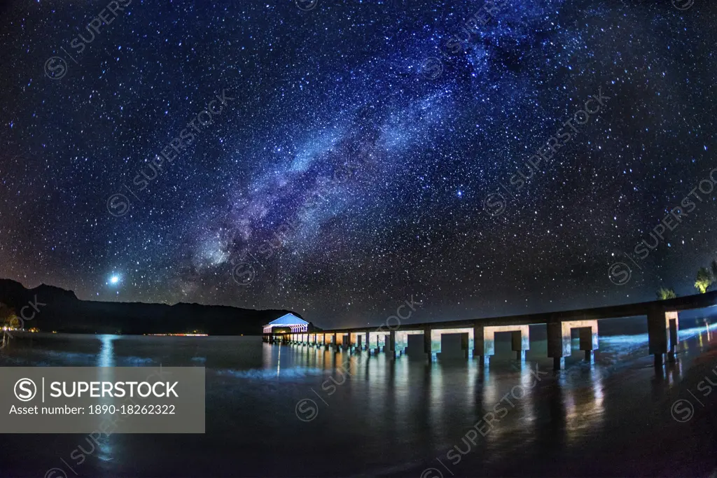 The Milky Way and Venus rise over the Hanalei Bay with the Hanalei Pier in the foreground lit by passing car headlights, Hanalei, Hawaii, United States of America, Pacific