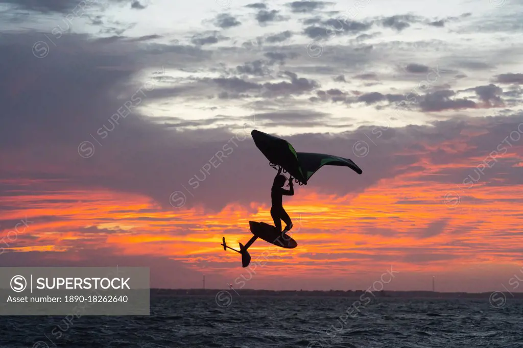 Pro surfer James Jenkins jumps his wing surfer at sunset over the Pamlico Sound at Nags Head, North Carolina, United States of America, North America