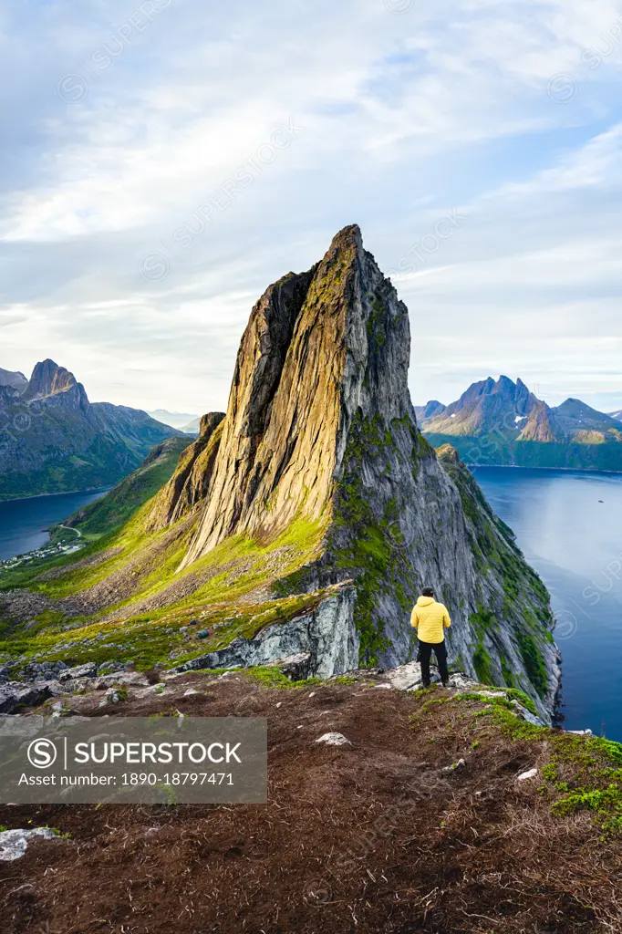 Person standing in front of tall Segla Mountain and fjords at dawn, Senja island, Troms county, Norway, Scandinavia, Europe