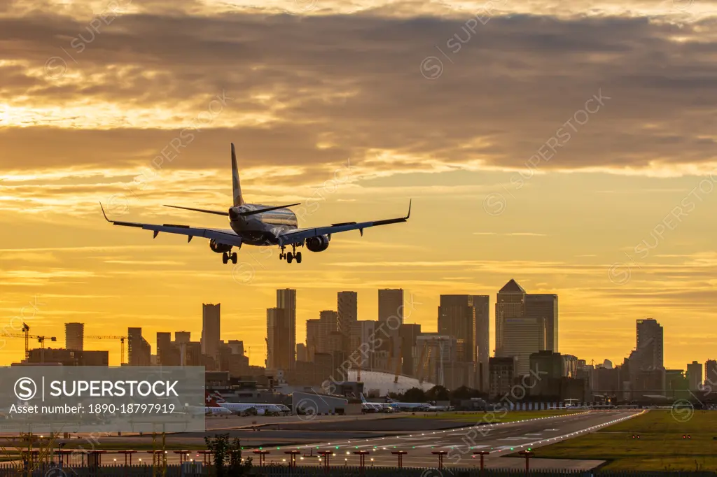 Aircraft landing at London City Airport at sunset, with Canary Wharf and O2 Arena in background, London, England, United Kingdom, Europe