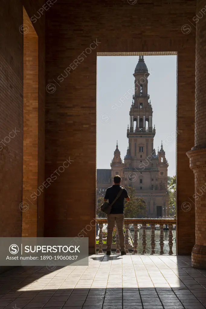 Man enjoying the view of Plaza de Espana, framed through an archway, Seville, Andalusia, Spain