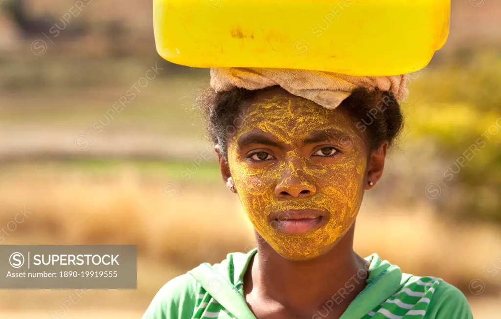 Portrait of woman carrying water, with her face painted to protect the skin from the sun, Isalo, Madagascar, Africa