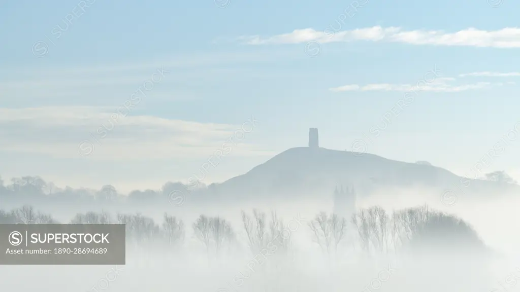 St. Michael's Tower on Glastonbury Tor above the tower of St. John the Baptist's Church on a misty morning in winter, Glastonbury, Somerset, England, United Kingdom, Europe