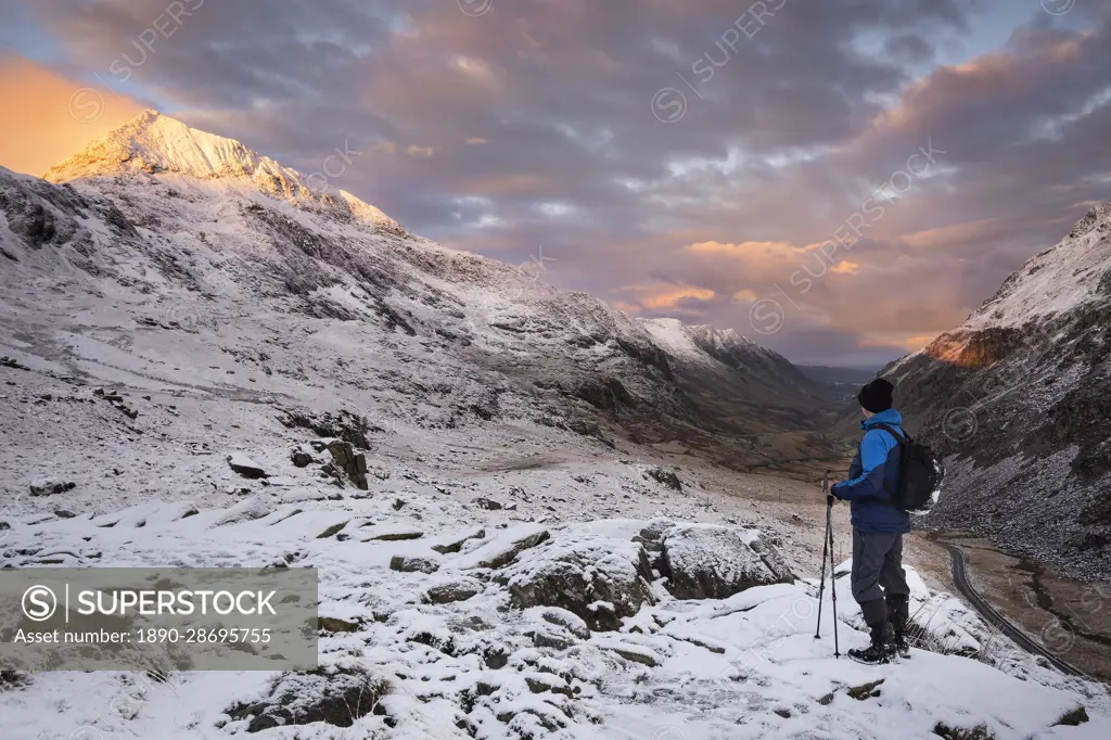 Walker looking to Crib Goch and the Llanberis Pass at dawn in winter, Snowdonia National Park, Eryri, North Wales, United Kingdom, Europe