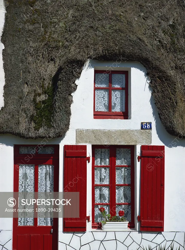 Exterior of a thatched cottage with red door and shutters in La Grande Briere, Ile de Fedrun, Pays de la Loire, France, Europe