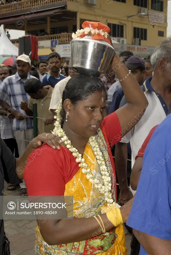 Pilgrim known as kavadi carrier is carrying container paal kudam of milk offerings during Hindu Thaipusam Festival from Sri Subramaniyar Swami Temple ...