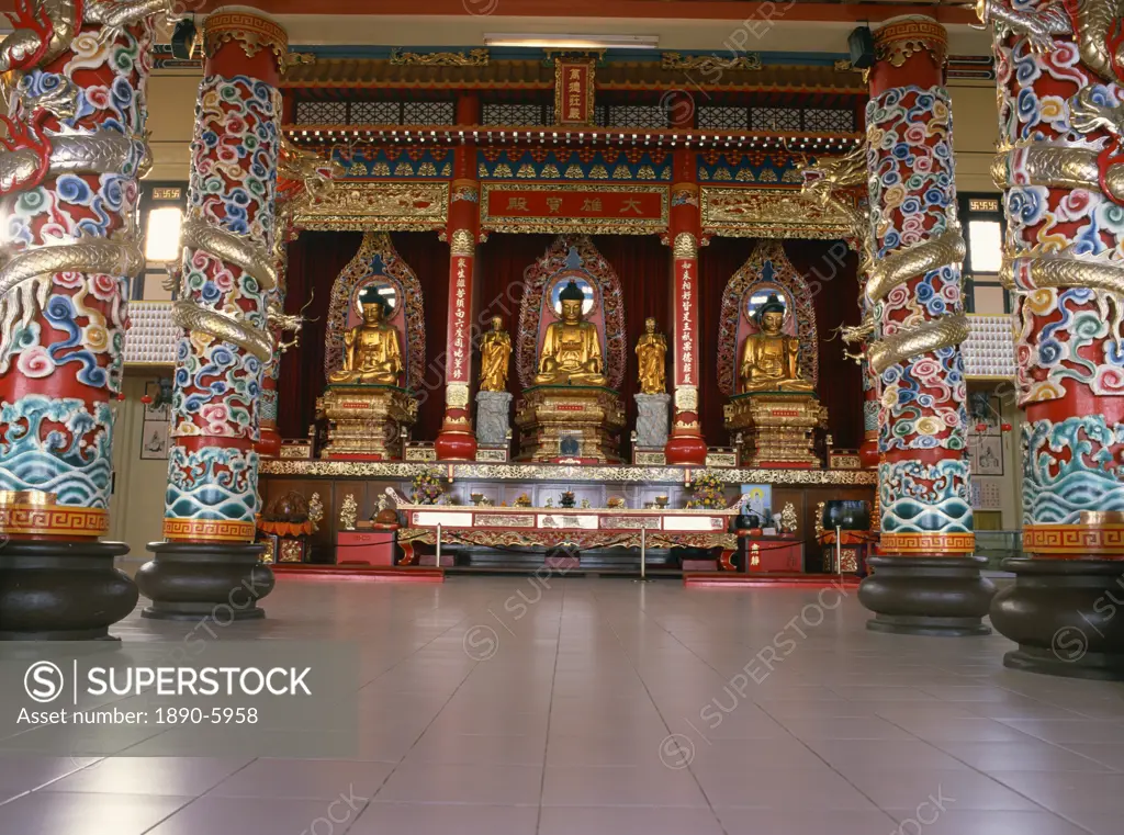 Three huge statues of Buddha of teak covered with gold foil, and dragon entwined pillars inside the Puu Jih Shih Temple, Sandakan, Sabah, Malaysia, So...