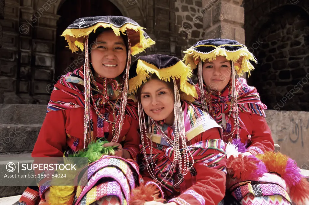 Portrait of three smiling Peruvian girls in traditional dance dress, looking at the camera, Cuzco, Peru, South America