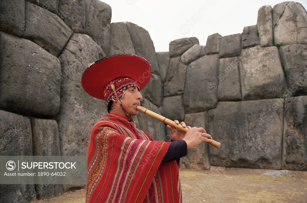 Portrait of a Peruvian man playing a flute, Inca ruins of Sacsayhuaman, near Cuzco, Peru, South America