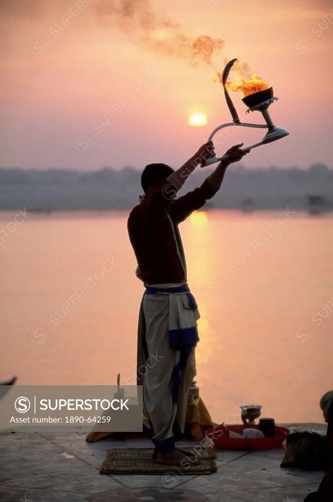 Hindu man worshipping in front of setting sun, River Ganges Ganga, Varanasi Benares, Uttar Pradesh state, India, Asia