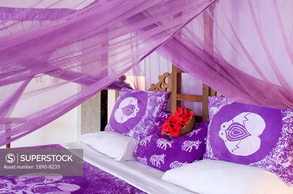 Purple mosquito netting and hibiscus flowers on a bed at the Shooting Star Hotel, Kiwendwa, Zanzibar, Tanzania, East Africa, Africa