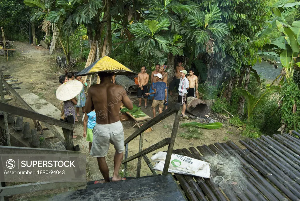 Iban tribal chief joins other villagers sharing a joke and cooking in the rain, Lemanak River, Sarawak, Malaysian Borneo, Malaysia, Southeast Asia, As...