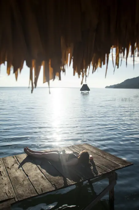 Woman relaxing on dock, El Remate, Lago Peten Itza, Guatemala, Central America