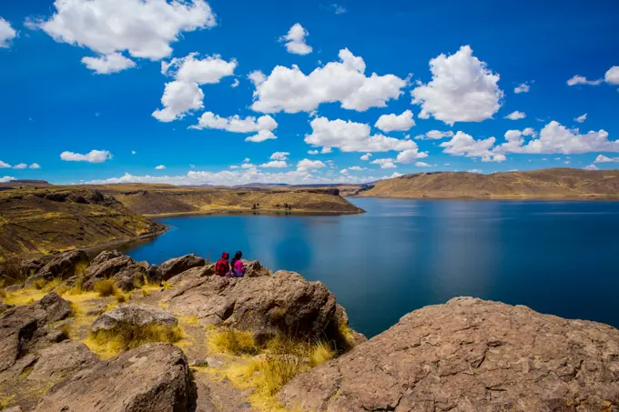 Two people sitting on the edge of Lake Titicaca, Peru, South America