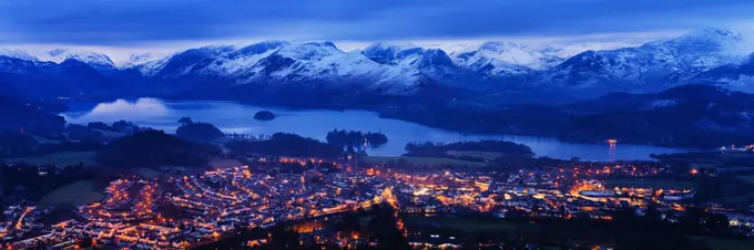 Looking over Keswick to Derwent Water and the snow capped mountains in the Lake District National Park at dusk, Cumbria, England, United Kingdom, Euro...