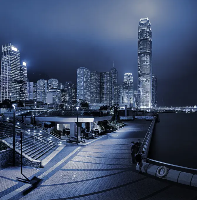 Central and Western district promenade leads through to skyscrapers on Hong Kong island above Victoria Harbour at night, Hong Kong, China, Asia