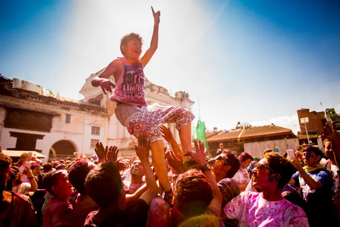 Boy being thrown in the air during the Holi Pigment Throwing festival in Durbar Square, Kathmandu, Nepal, Asia