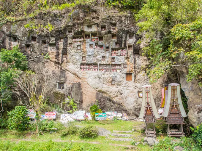 At this burial cliff, condolence signs from past funerals and coffin carriers shaped like traditional Torajan houses are left below the crypts and tao...