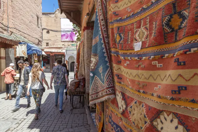 Tourists and locals walking alongside traditional rugs in the Medina's souks, Marrakech, Morocco, North Africa, Africa