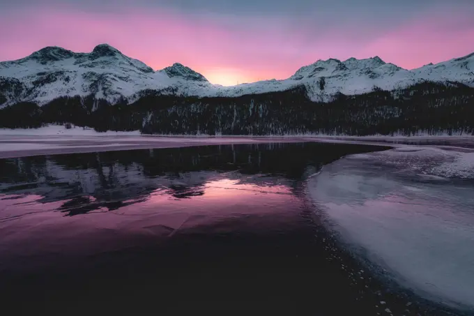 Colorful sky at sunrise on snowcapped mountains and frozen Lake Silvaplana, Maloja, Engadine, Graubunden canton, Switzerland, Europe