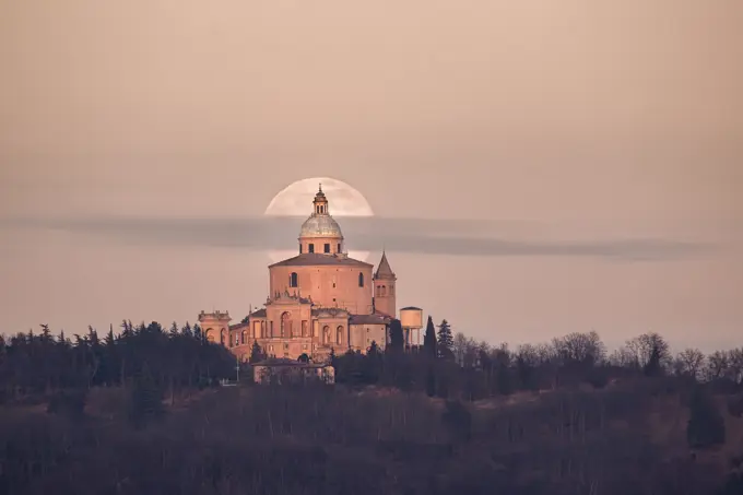 Full moon and a small cloud behind San Luca church (Madonna di San Luca). Bologna, Italy, Europe