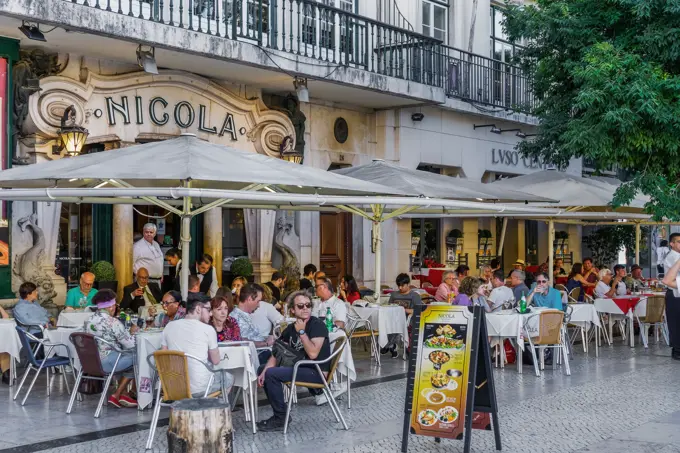 Historic Cafe Nicola entrance with art deco facade and seated customers at outdoor tables in Rossio Square, Lisbon, Portugal, Europe