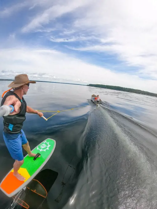 Photographer Skip Brown rides his hydrofoil behind a small boat on Sebago Lake, Maine, United States of America, North America