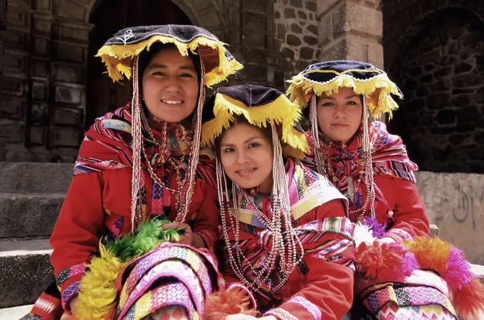 Portrait of three smiling Peruvian girls in traditional dance dress, looking at the camera, Cuzco, Peru, South America