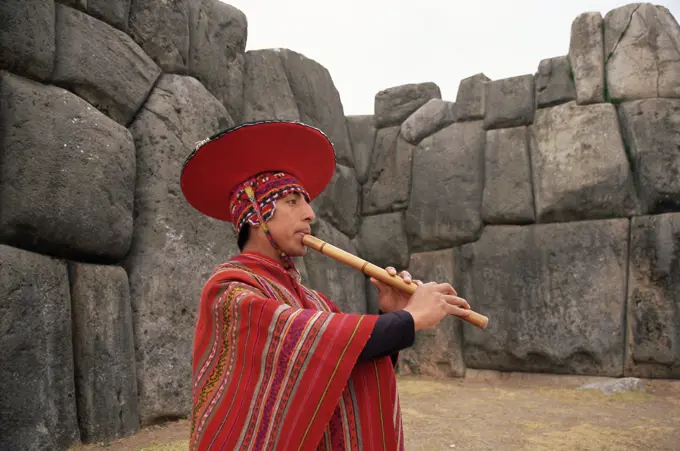 Portrait of a Peruvian man playing a flute, Inca ruins of Sacsayhuaman, near Cuzco, Peru, South America